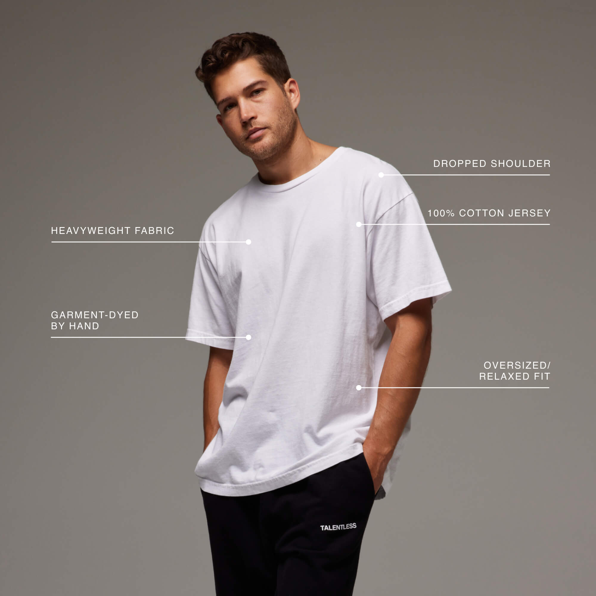 Model wearing the Drop Shoulder Tee with descriptive tags which demonstrate that it's 100% cotton, dropped shoulders and relaxed fit